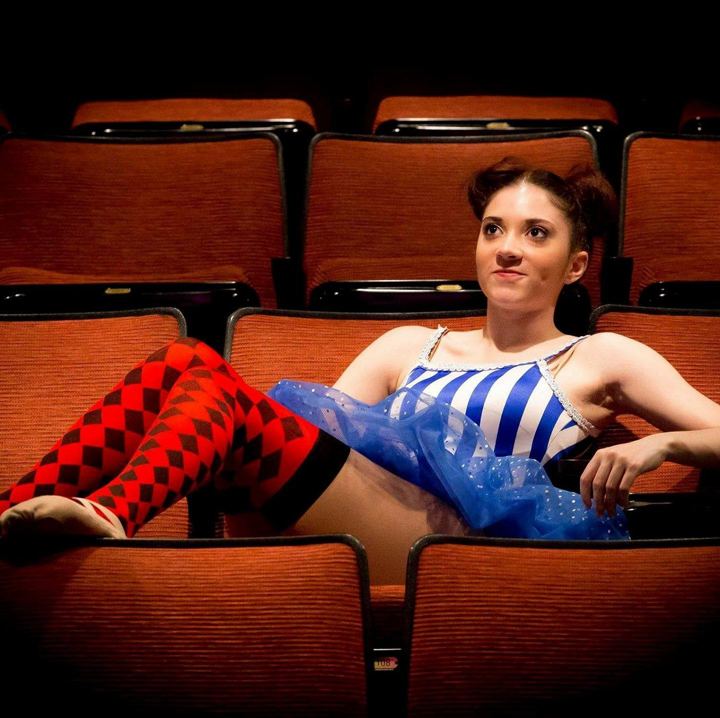 Lexi lounging across theater seats in a striped circus costume