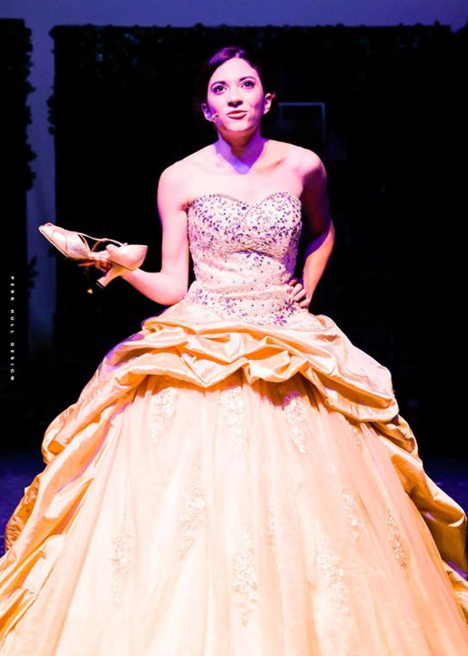 Lexi on stage as Cinderella in a gold ball gown, holding a slipper