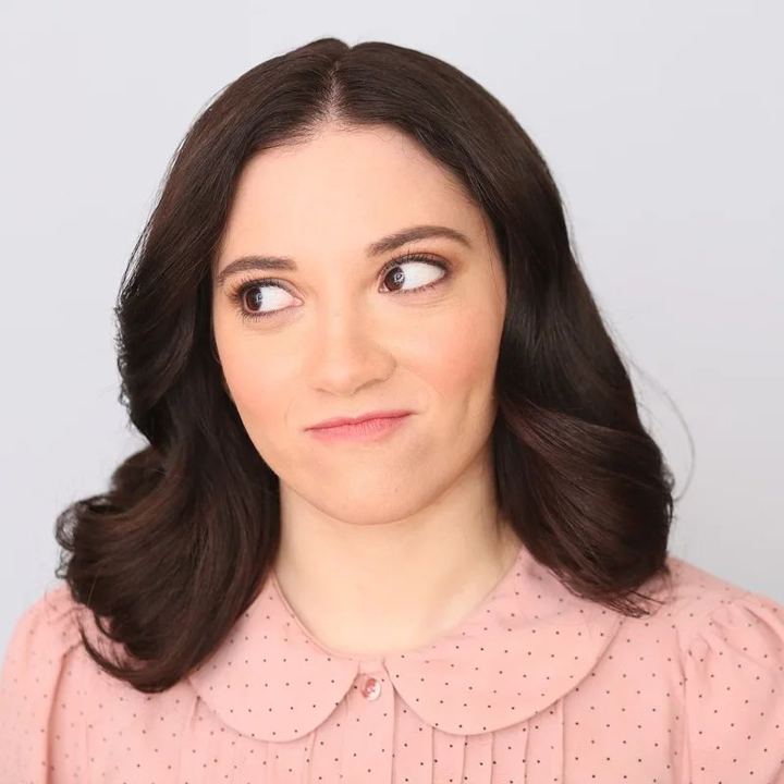 Lexi giving a skeptical side-eye in a pink collared blouse